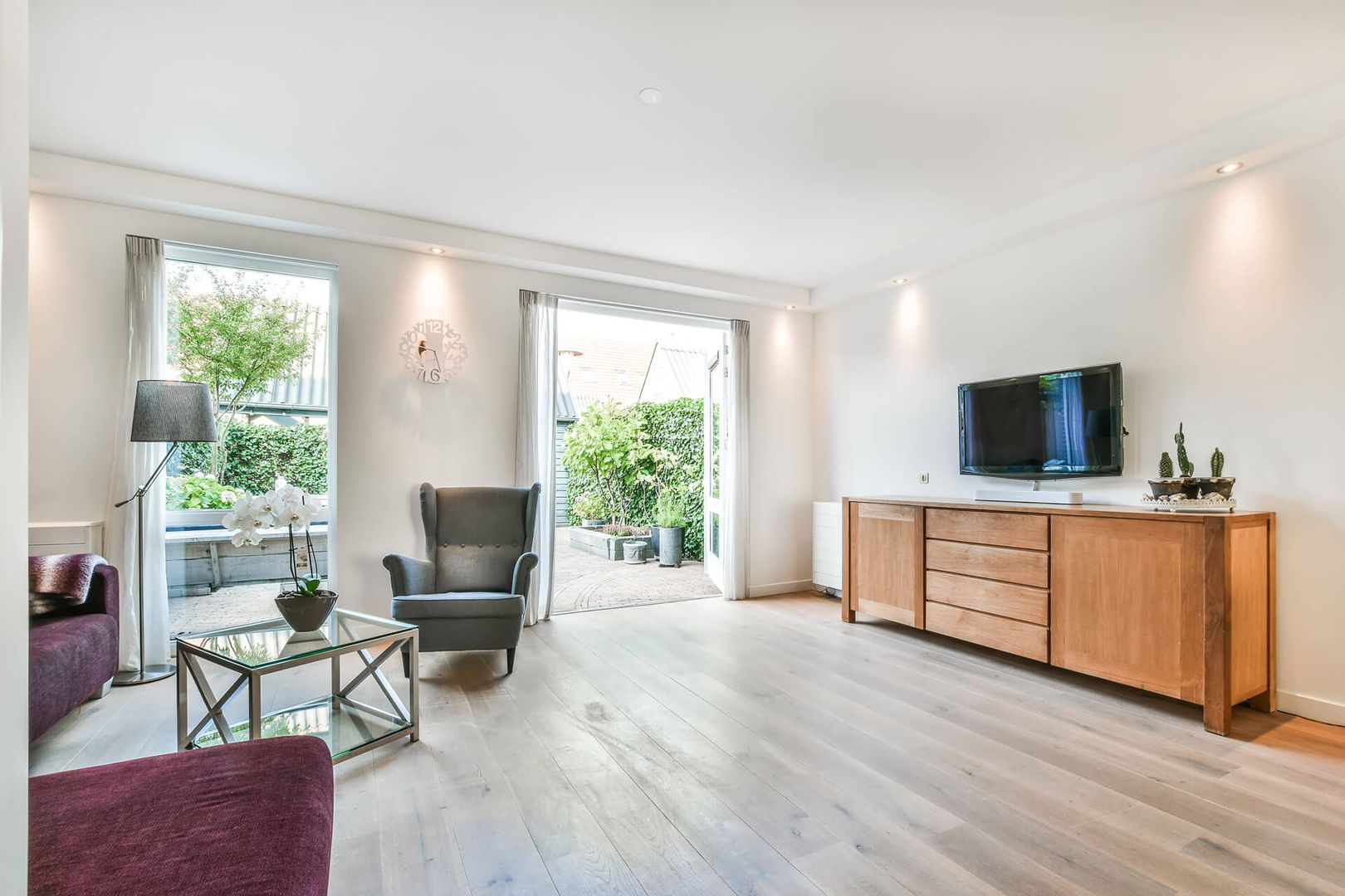 Helles Wohnzimmer mit weißen Wänden, Holzmöbeln und großzügigem Lichteinfall